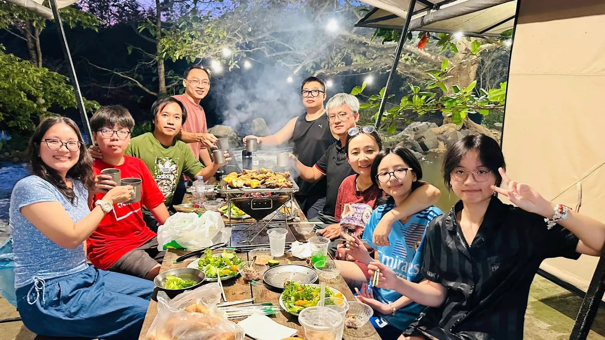 Nhóm khách quây quần bên bàn BBQ buổi tối, cười vui cùng món nướng